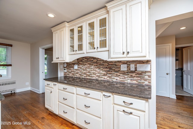 2 Darroch Rd, Bethlehem, NY 12054 - kitchen with radiator heating unit, dark wood-style flooring, backsplash, glass insert cabinets, and baseboards