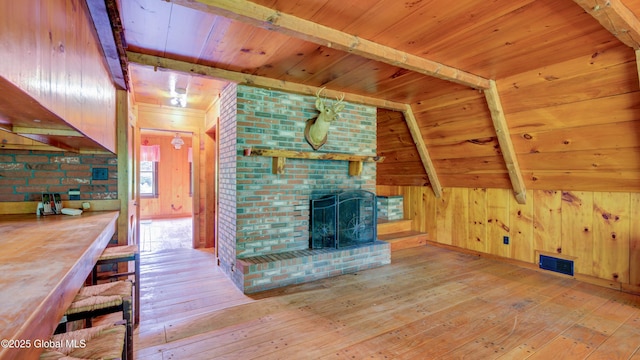 824 County Highway 106, Mayfield, NY 12010 - unfurnished living room with light wood-type flooring, wood ceiling with exposed beams, wooden walls, and a brick fireplace