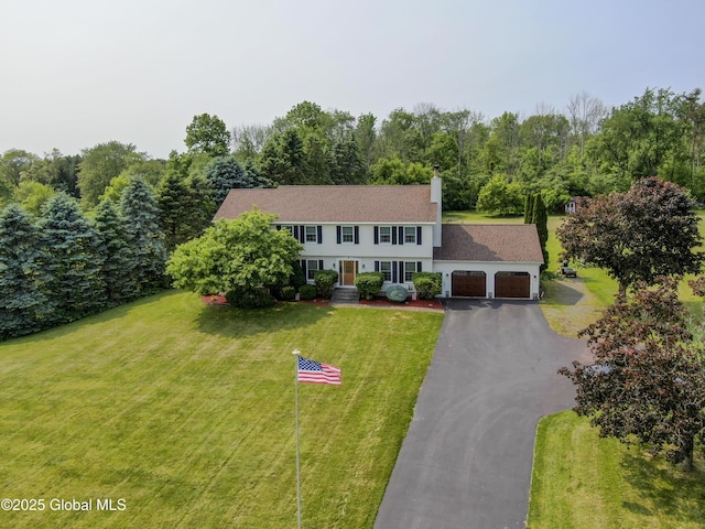 540 Mohawk Dr, Mohawk, NY 12068 - colonial inspired home featuring a garage, asphalt driveway, a chimney, a front lawn, and a wooded view