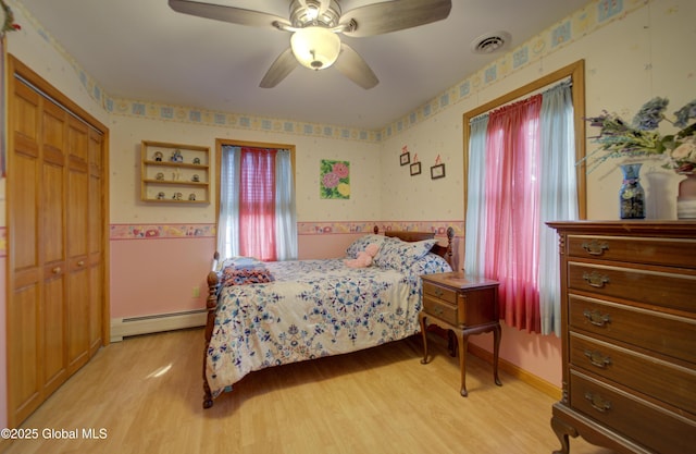 540 Mohawk Dr, Mohawk, NY 12068 - bedroom featuring a baseboard radiator, wallpapered walls, light wood-type flooring, a closet, and a ceiling fan