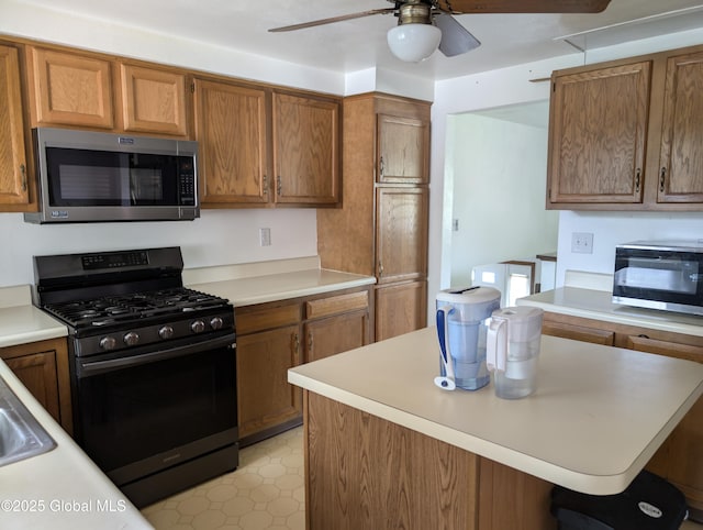 2714 Magnolia St, Endicott, NY 13760 - kitchen with stainless steel microwave, black gas range oven, a ceiling fan, and light countertops