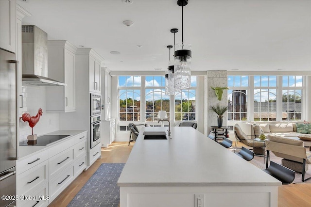 268 Broadway Unit 607, Saratoga Springs, Inside, NY 12866 - kitchen with wall chimney exhaust hood, built in appliances, open floor plan, a sink, and a kitchen island with sink