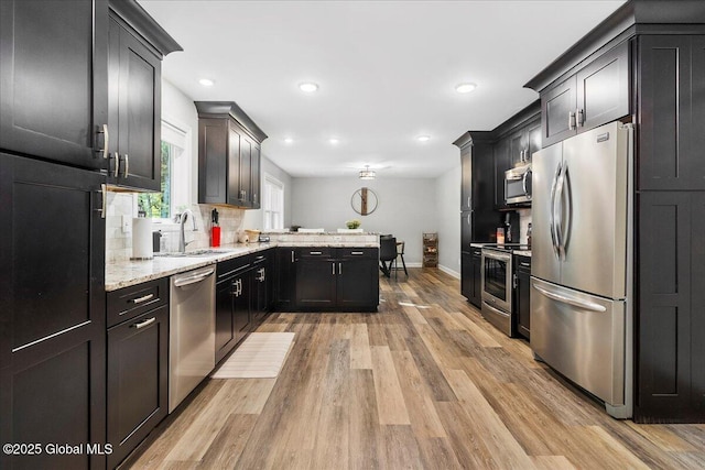 32 Kara Ln, Clifton Park, NY 12065 - kitchen with stainless steel appliances, a sink, baseboards, a peninsula, and light wood-style flooring