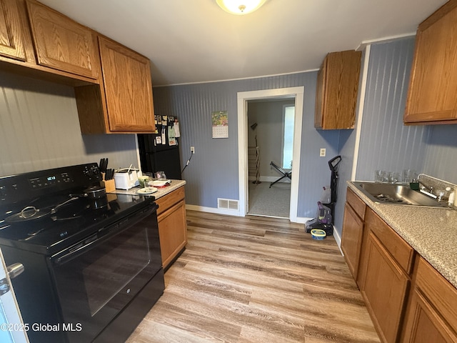 32 5th Ave, Gloversville, NY 12078 - kitchen with black appliances, a sink, light wood-type flooring, light countertops, and brown cabinets
