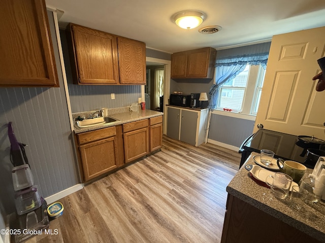 32 5th Ave, Gloversville, NY 12078 - kitchen featuring a sink, brown cabinets, light wood-style flooring, and baseboards