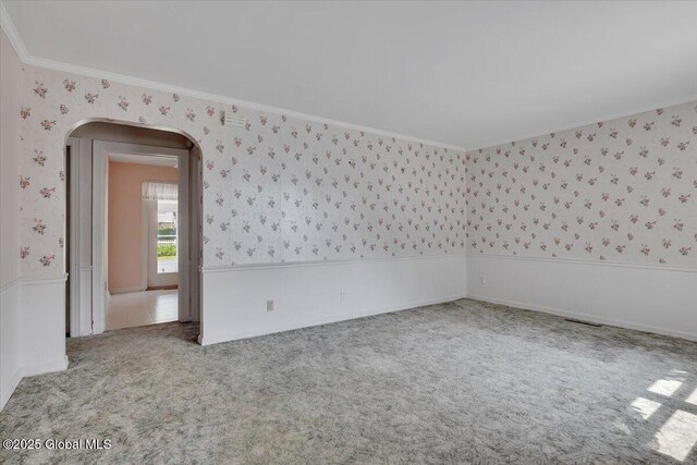 327 Sullivan Rd, Schenectady, NY 12304 - empty room featuring wallpapered walls, arched walkways, crown molding, carpet floors, and wainscoting