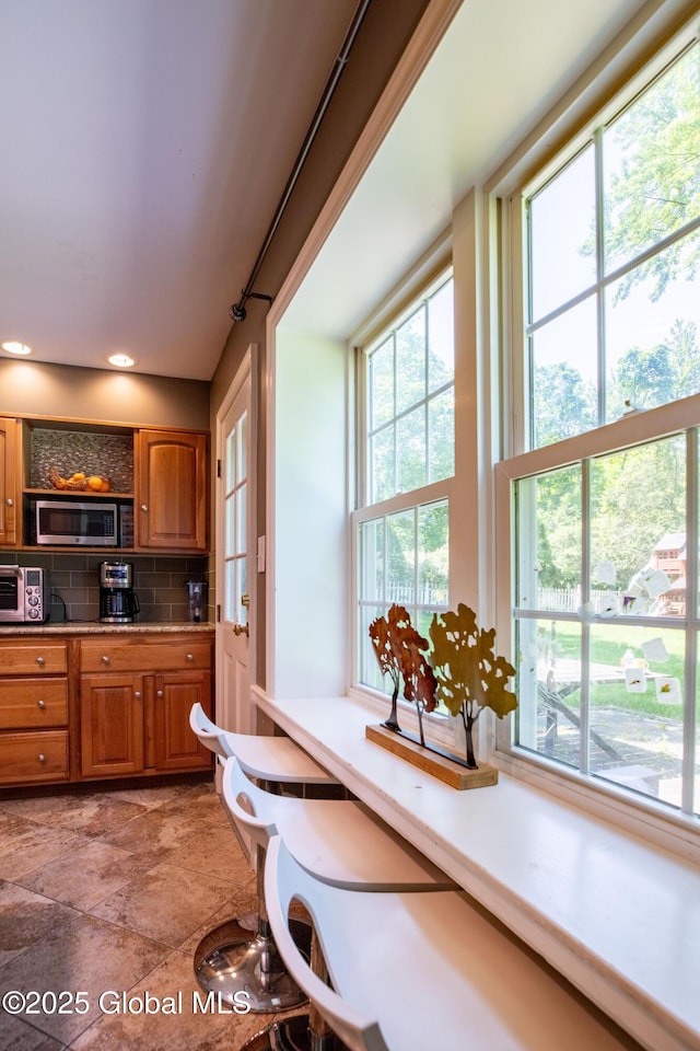 1269 Hawthorn Rd, Niskayuna, NY 12309 - kitchen featuring stainless steel microwave, brown cabinetry, decorative backsplash, and light countertops