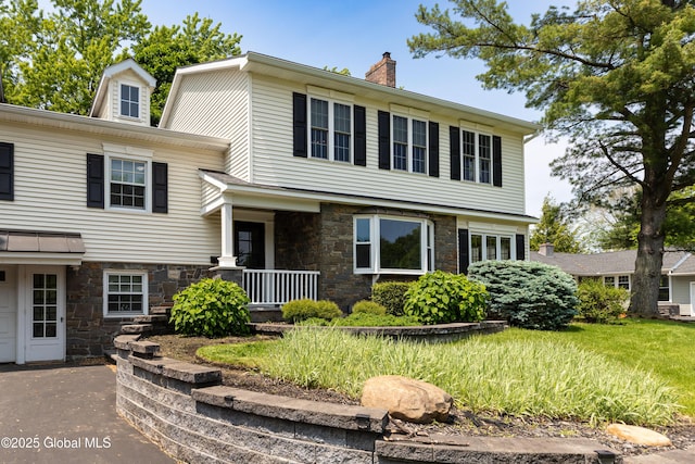 1269 Hawthorn Rd, Niskayuna, NY 12309 - view of front facade featuring stone siding, a chimney, and covered porch