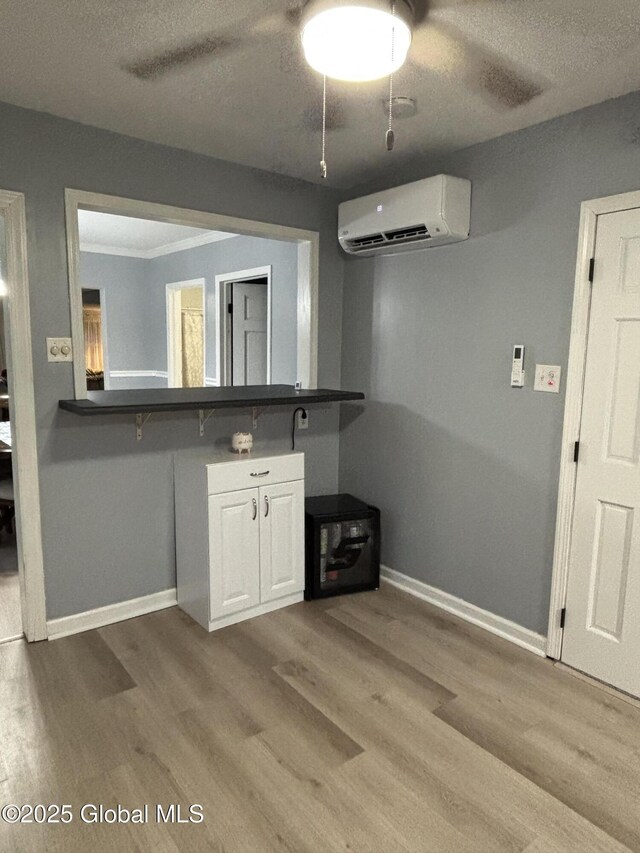 3516 Consaul Rd, Schenectady, NY 12304 - kitchen with an AC wall unit, wood finished floors, baseboards, white cabinets, and dark countertops