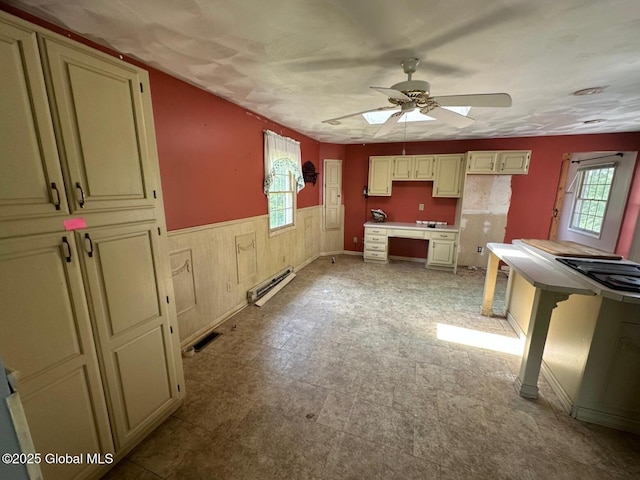 6770 Obrien Rd, Rome, NY 13440 - kitchen featuring baseboard heating, plenty of natural light, ceiling fan, cream cabinetry, and a wainscoted wall