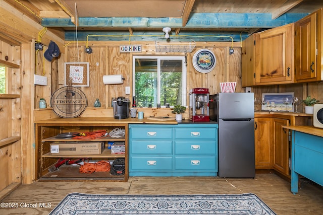 44 St Jude Ln, Glenville, NY 12302 - kitchen featuring freestanding refrigerator, plenty of natural light, wooden walls, light wood-style flooring, and brown cabinetry