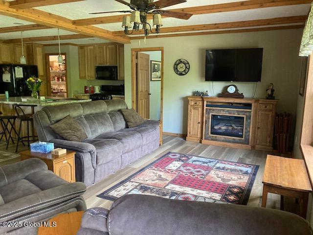 841 Battle Hill Rd, Hague, NY 12836 - living area with ceiling fan, light wood-style flooring, beamed ceiling, and a glass covered fireplace