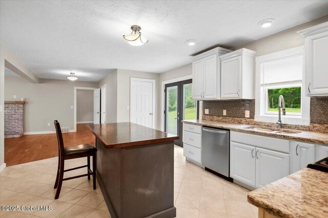 61 Lemaire Way, Argyle, NY 12809 - kitchen featuring stainless steel dishwasher, decorative backsplash, a breakfast bar, white cabinets, and a center island