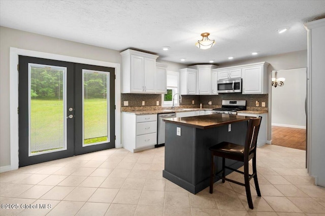 61 Lemaire Way, Argyle, NY 12809 - kitchen with stainless steel appliances, french doors, backsplash, white cabinetry, and a kitchen island