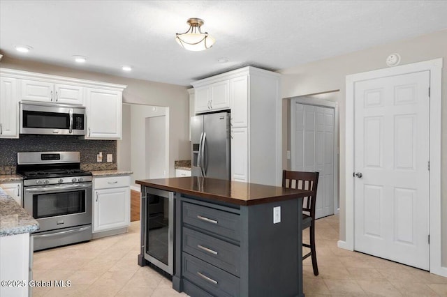 61 Lemaire Way, Argyle, NY 12809 - kitchen featuring stainless steel appliances, beverage cooler, white cabinetry, light tile patterned floors, and tasteful backsplash