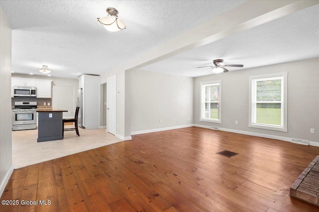 61 Lemaire Way, Argyle, NY 12809 - unfurnished living room with light wood-type flooring, ceiling fan, and a textured ceiling