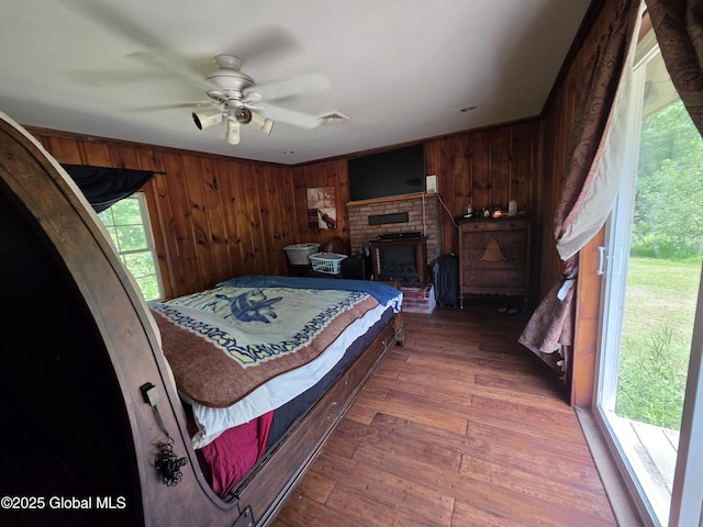 3841 State Highway 30, Mayfield, NY 12010 - bedroom with wooden walls, hardwood / wood-style floors, ceiling fan, and a brick fireplace
