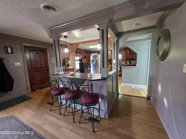 3841 State Highway 30, Mayfield, NY 12010 - kitchen featuring decorative columns, crown molding, a breakfast bar, wood finished floors, and baseboards