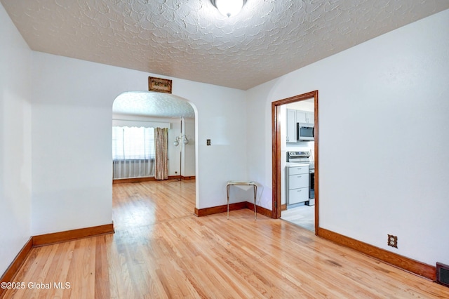 55 Crescent Ave, Amsterdam, NY 12010 - empty room with arched walkways, light wood-style flooring, baseboards, and a textured ceiling