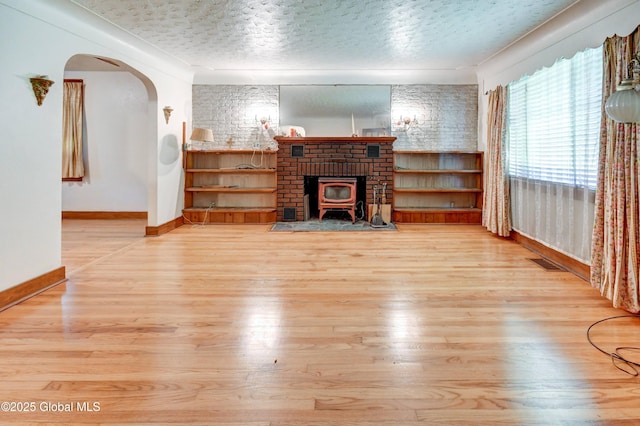 55 Crescent Ave, Amsterdam, NY 12010 - living room with baseboards, wood finished floors, a textured ceiling, arched walkways, and a wood stove