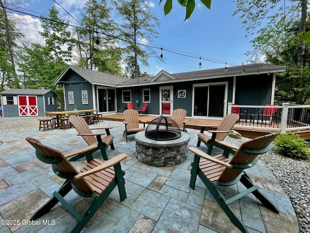 3602 Echo Bay Ln, Fort Ann, NY 12844 - back of property featuring a fire pit, a storage unit, a patio area, outdoor dining space, and a shingled roof