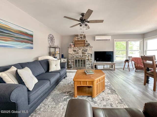 3602 Echo Bay Ln, Fort Ann, NY 12844 - living area with an AC wall unit, a ceiling fan, wood finished floors, and a stone fireplace
