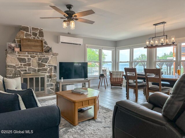 3602 Echo Bay Ln, Fort Ann, NY 12844 - living room featuring a wall mounted AC, ceiling fan, wood finished floors, a stone fireplace, and a chandelier
