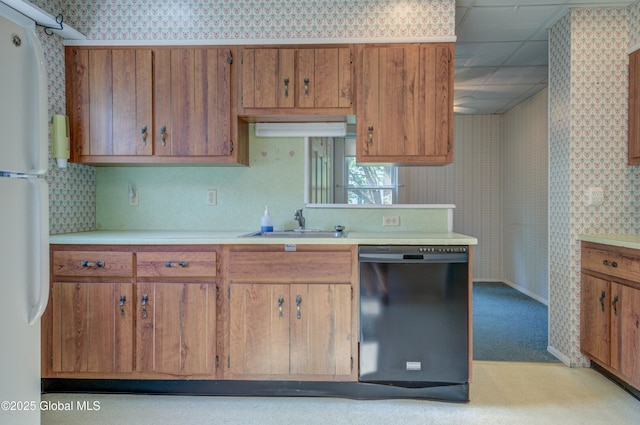510 S William St, Johnstown, NY 12095 - kitchen with black dishwasher, wallpapered walls, freestanding refrigerator, light countertops, and brown cabinets