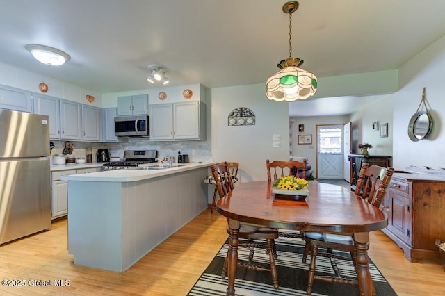 8 Birchtree Ln, Milton, NY 12020 - kitchen featuring stainless steel appliances, a peninsula, light countertops, decorative backsplash, and light wood-type flooring