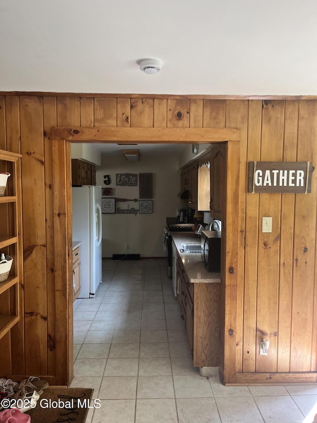 6 Pine Rd, Moreau, NY 12803 - kitchen featuring white fridge with ice dispenser, wooden walls, brown cabinetry, light tile patterned floors, and range with gas cooktop