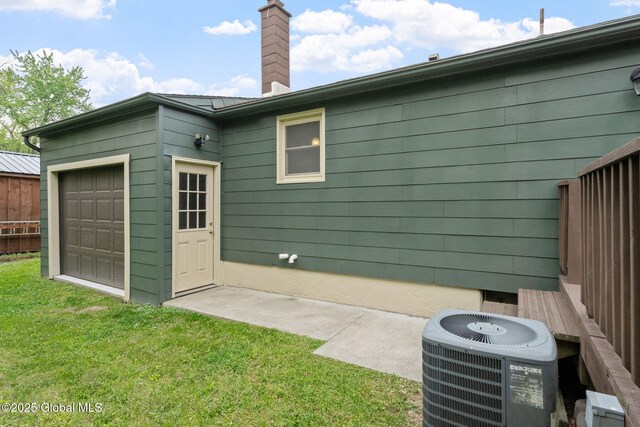 16 Smith Ln, East Greenbush, NY 12144 - rear view of house featuring central air condition unit, a chimney, a yard, and a garage