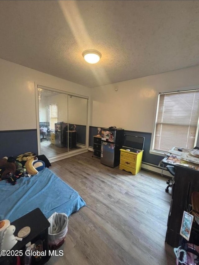 13 Hawk St, Amsterdam, NY 12010 - bedroom featuring wood finished floors, multiple windows, a closet, baseboard heating, and a textured ceiling