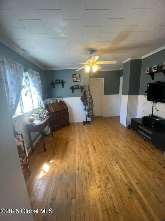 13 Hawk St, Amsterdam, NY 12010 - bedroom featuring wainscoting, ornamental molding, wood-type flooring, baseboard heating, and ceiling fan