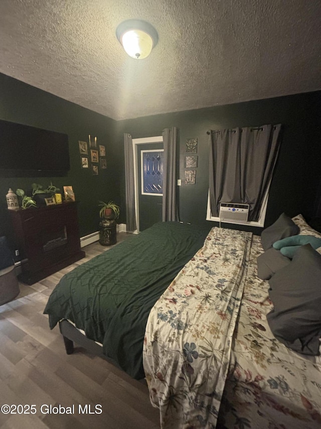 13 Hawk St, Amsterdam, NY 12010 - bedroom featuring a baseboard heating unit, a textured ceiling, wood finished floors, baseboards, and a wall mounted air conditioner
