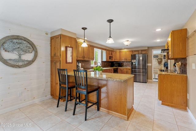 1396 Barton Hill Rd, Wright, NY 12053 - kitchen featuring stainless steel fridge with ice dispenser, a peninsula, brown cabinetry, tasteful backsplash, and light stone counters