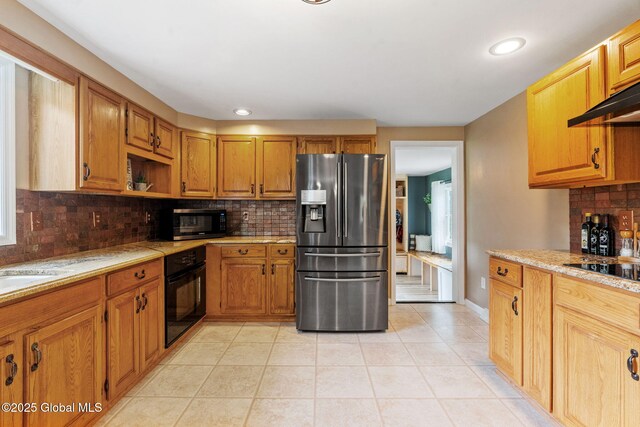 1396 Barton Hill Rd, Wright, NY 12053 - kitchen featuring black appliances, backsplash, light tile patterned floors, brown cabinetry, and light stone countertops