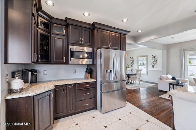 195 W Circular St, Saratoga Springs, NY 12866 - kitchen with stainless steel appliances, dark brown cabinetry, recessed lighting, glass insert cabinets, and light tile patterned floors