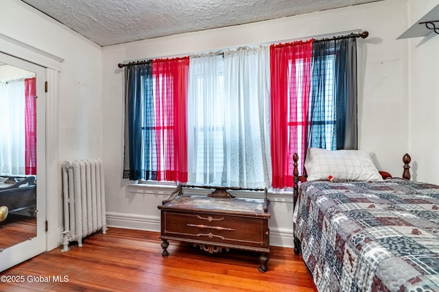 58 N Allen St, Albany, NY 12203 - bedroom with radiator heating unit, wood finished floors, baseboards, and a textured ceiling