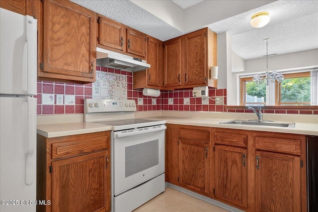 35 Justine Ct, East Greenbush, NY 12144 - kitchen featuring white appliances, under cabinet range hood, brown cabinetry, a textured ceiling, and decorative backsplash