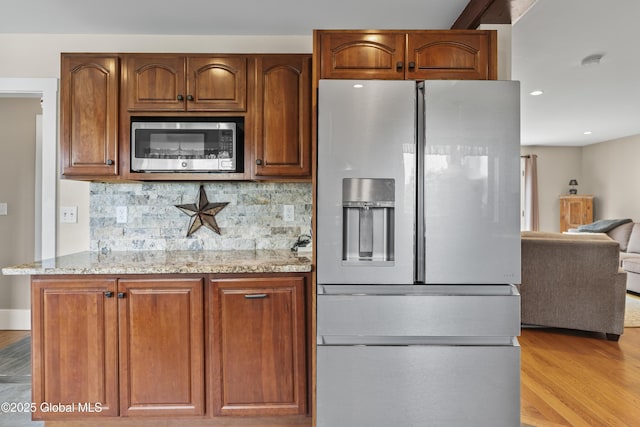 363 Goodman Rd, Fort Ann, NY 12827 - kitchen featuring stainless steel appliances, light wood-type flooring, light stone counters, tasteful backsplash, and brown cabinets