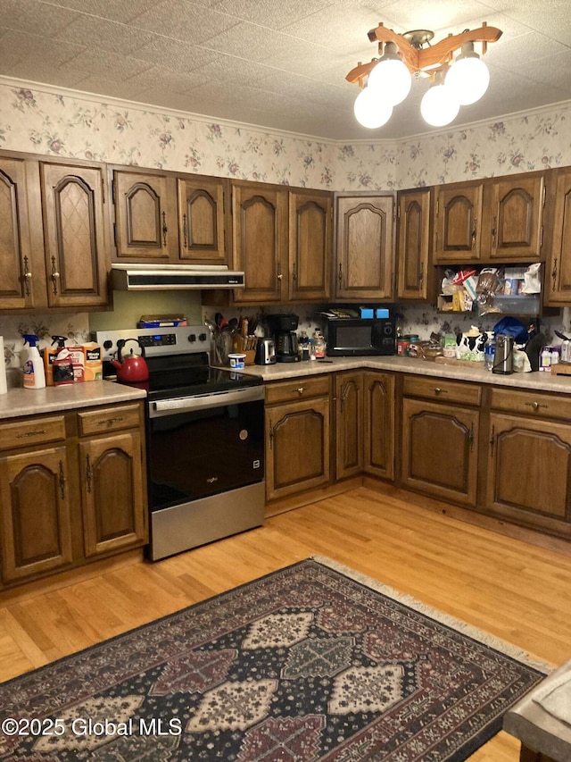 48 Spring St, Port Henry, NY 12974 - kitchen featuring stainless steel range with electric stovetop, ventilation hood, black microwave, a chandelier, and light wood-style floors