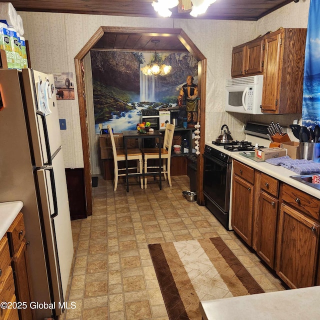 1948 Leo Ave, Rotterdam, NY 12306 - kitchen with white appliances, wallpapered walls, a chandelier, light countertops, and brick patterned floors