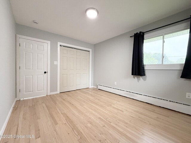 10 Kasper Dr, Colonie, NY 12211 - unfurnished bedroom featuring baseboard heating, light wood-style floors, baseboards, and a closet