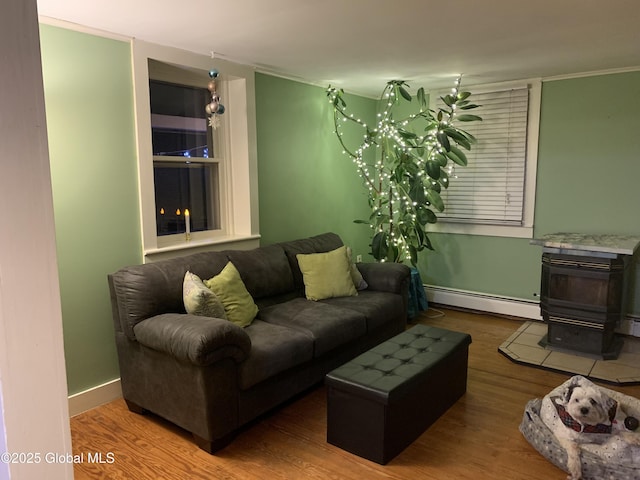 3 Meacham St, Port Henry, NY 12974 - living area featuring a baseboard radiator, a wood stove, wood finished floors, and baseboards