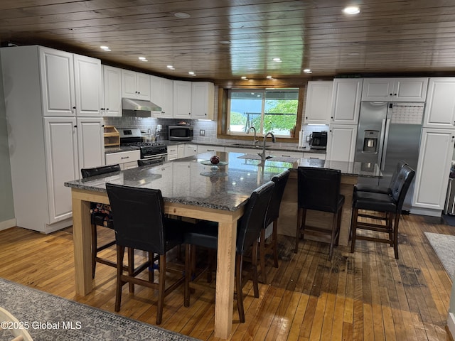3 Meacham St, Port Henry, NY 12974 - kitchen with stainless steel appliances, under cabinet range hood, dark wood-style flooring, a kitchen bar, and wood ceiling