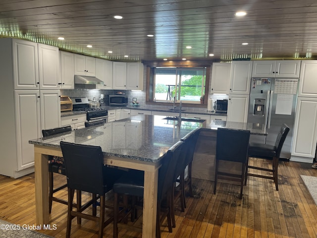 3 Meacham St, Port Henry, NY 12974 - kitchen with stainless steel appliances, under cabinet range hood, hardwood / wood-style floors, and a breakfast bar