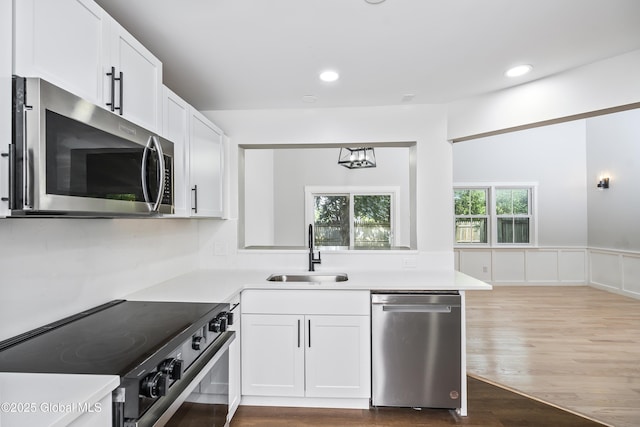21 Jaipur Ln, Saratoga Springs, NY 12866 - kitchen with appliances with stainless steel finishes, wood finished floors, light countertops, white cabinets, and a wainscoted wall