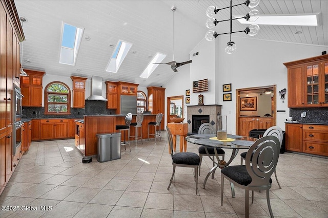 2034 Duanesburg Churches Rd, Duanesburg, NY 12053 - kitchen with wall chimney range hood, a skylight, brown cabinets, a kitchen breakfast bar, and backsplash