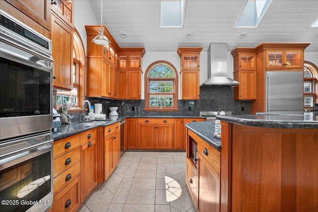 2034 Duanesburg Churches Rd, Duanesburg, NY 12053 - kitchen with wall chimney exhaust hood, stainless steel appliances, brown cabinetry, and a skylight