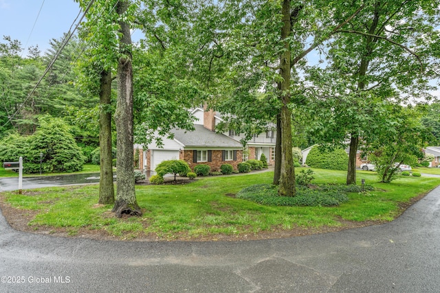 19 Tamarack Ln, Colonie, NY 12309 - obstructed view of property with a front lawn, an attached garage, brick siding, and a chimney
